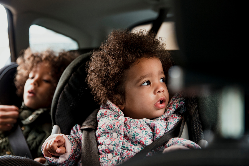 Two young children in the back of the car in separate car seats