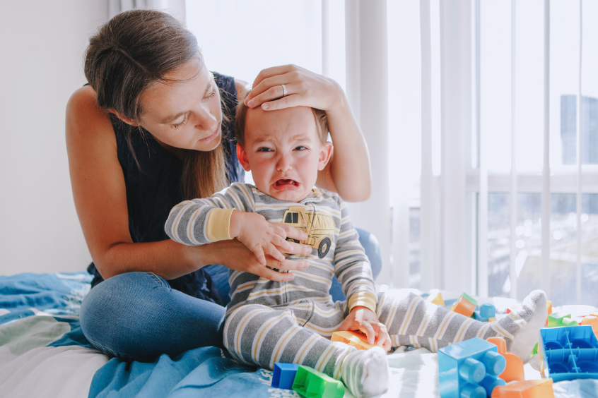 Mother hugging and pacifying upset crying toddler son