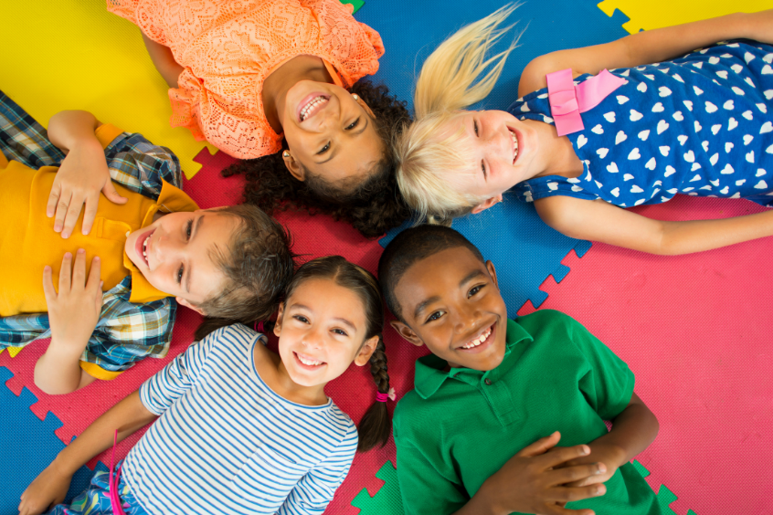 Diverse group of children laying down looking up at the camera