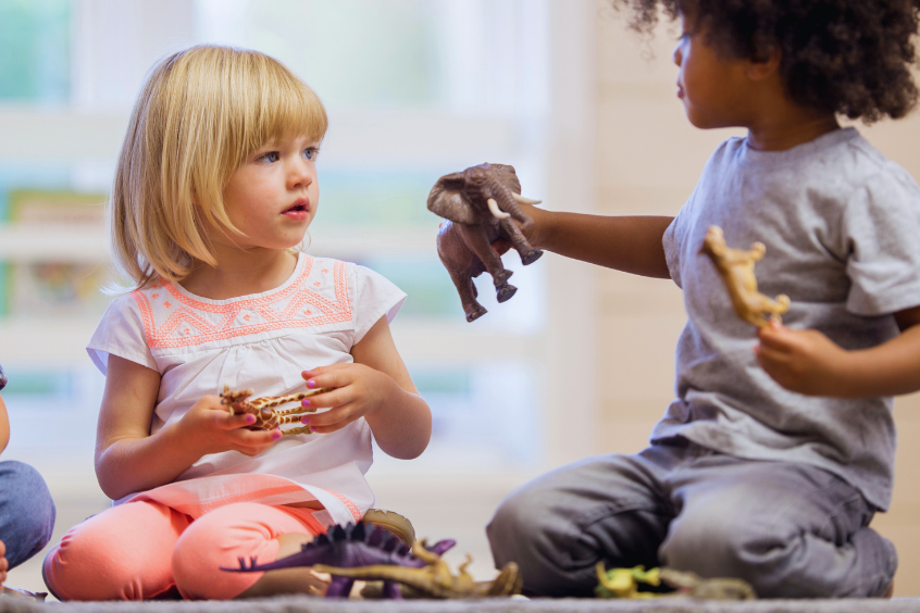Children playing together and sharing with plastic animal toys at day care