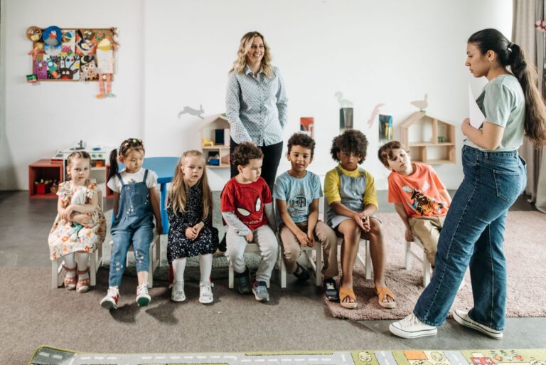 Group of diverse children in a kindergarten classroom attending an interactive learning session with teachers.