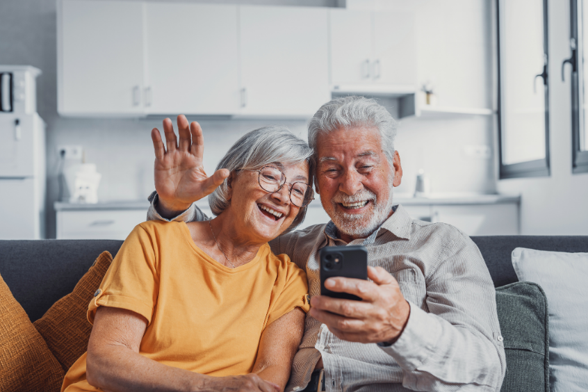 Happy senior couple talking to someone on the phone via video call