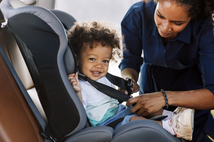 Mother strapping son safely into the car seat